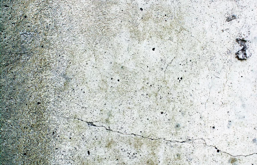 Close view of a weathered concrete wall face showing several fine horizontal hairline cracks